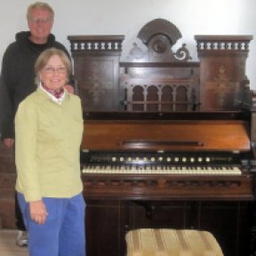 Photo of Georgia Kestol Bauer and Rev. Larry Froemming with a 19th century Estey Pump Organ